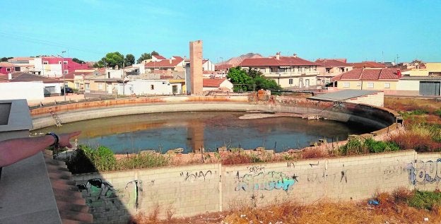 La balsa de El Botijón, con el agua estancada, junto a numerosas viviendas en Balsicas.