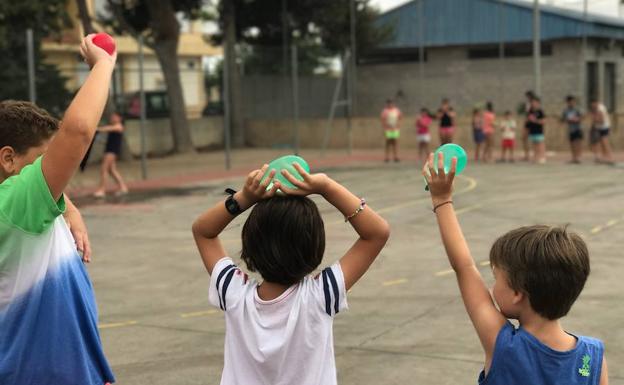 Un grupo de escolares se divierte con globos de agua en la Escuela de Verano.
