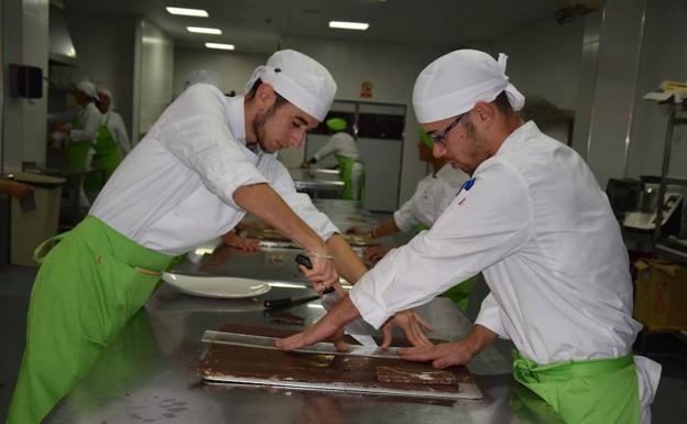 Dos alumnos del programa de pastelería preparan turrón de chocolate. /A.Salas