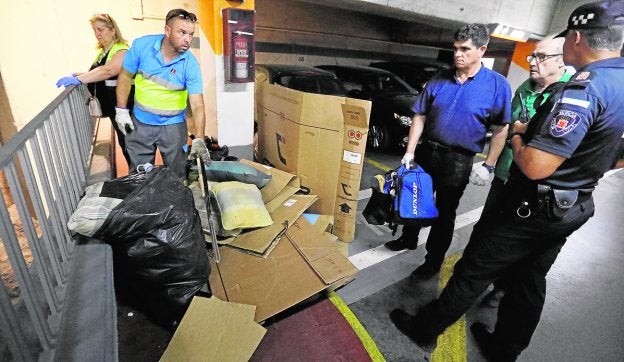 Operarios retiran enseres y cartones del parking, bajo vigilancia de la Policía Local.