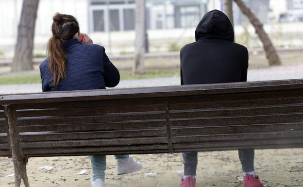 Dos jóvenes en un parque sentados en un banco.