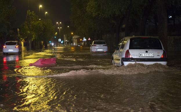 Vehículos circulan con dificultad por la calle Mariano Rojas de Murcia anegada por el agua.