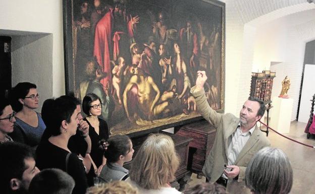 Visitantes atienden las explicaciones del director de la musealización del palacio en una exposición con piezas ya restauradas.