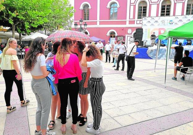 Un grupo de jóvenes se protegen de la lluvia debajo de un paraguas en la plaza de Calderón de la Barca.