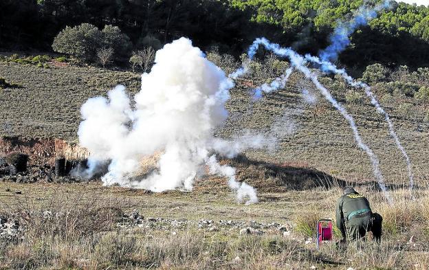 Neutralización. Un artefacto explosivo semioculto en la vegetación. En la imagen superior, un artificiero de la Guardia Civil realiza una explosión controlada en un terreno acotado y desalojado. / gonzález molero