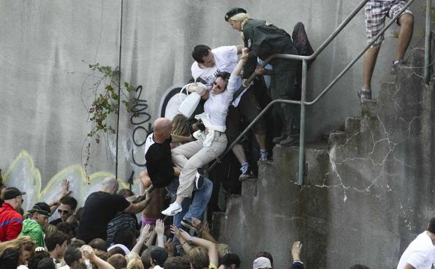 Una mujer es rescatada de la multitud por policías y civiles en la Love Parade de 2010. /Daniel Naupold (Reuters)