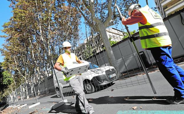 Dos obreros colocan las vallas para trabajar en un lateral del paseo Alfonso X./Edu Botella / AGM