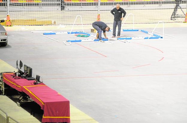 Dos operarios municipales montando las porterías, anoche en la pista principal del Palacio de Deportes. A la derecha, zona de minusválidos y cámaras./ Antonio Gil / AGM