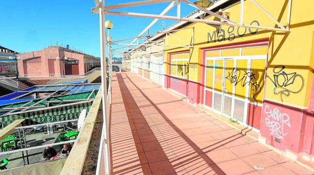 Locales cerrados en la primera planta del centro comercial; abajo, terrazas de algunos de los pocos comercios abiertos./Antonio Gil / AGM