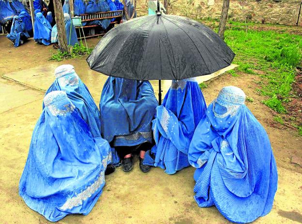 Con burka. Un grupo de mujeres afganas esperan para recibir ayuda humanitaria en Kabul./EFE