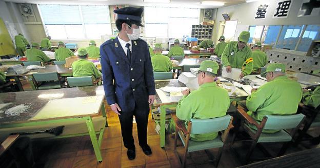 Un guardián vigila el taller de la cárcel de Onomichi, donde trabajan ancianos reclusos japoneses. / AFP El almuerzo en Onomichi discurre en absoluto silencio. :: AFP