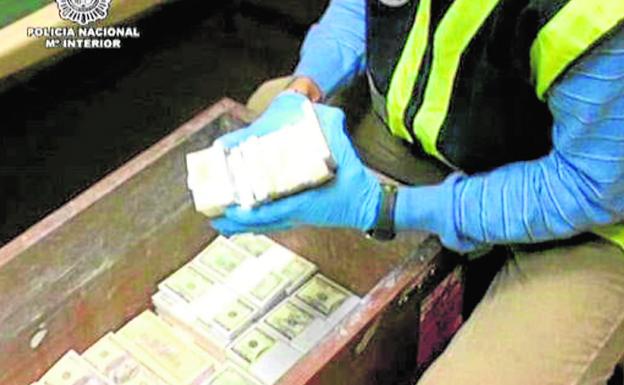 Un policía cuenta los fajos de billetes incautados a una banda de estafadores nigerianos / cnp