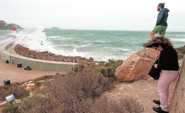 Un hombre y una mujer observan el fuerte oleaje que choca contra el Faro de Navidad./Antonio Gil / AGM