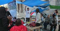 Un grupo de 'indignados', bajo toldos y junto a una pancarta con el lema 'Democracia real ya', junto al Palacio Consistorial. :: PABLO SÁNCHEZ / AGM/