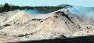 El montón de masa forestal que arde desde el 7 de septiembre, ayer, emanando humo. :: I. SÁNCHEZ / AGM/