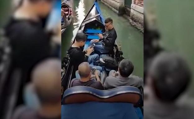 Turistas que montan en góndola para pasarse el viaje mirando el móvil