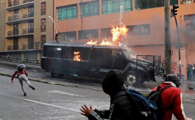 Los manifestantes atacan con bombas incendiarias una tanqueta de la Policía./Reuters