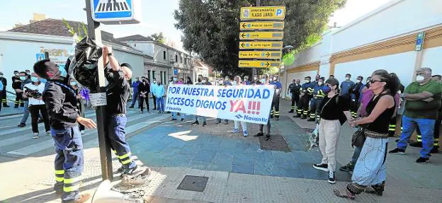 Two Navantia workers place a bouquet of flowers at the sign that warns of the proximity of the pedestrian crossing where their colleague from the committee was run over.  On the right, relatives of Óscar Rodríguez. 