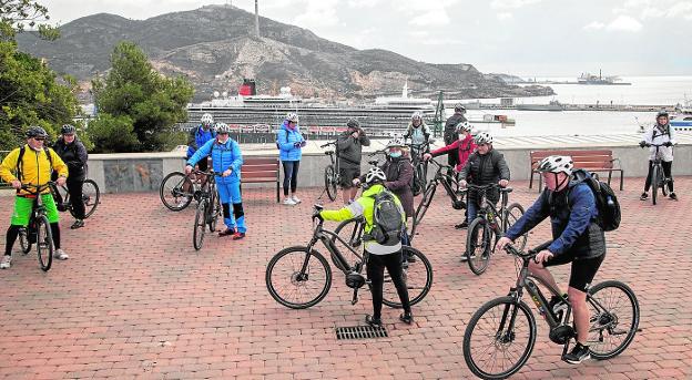 A group of tourists on bicycles, at the Torres Park viewpoint, with the transatlantic 'Queen Elizabeth' in the background, docked at the cruise ship dock. 