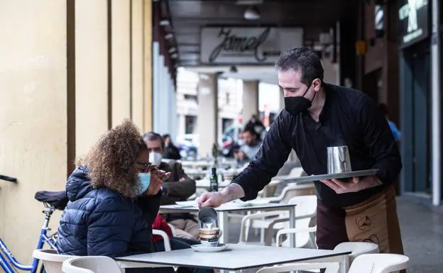 A waiter serves a coffee on a terrace. 
