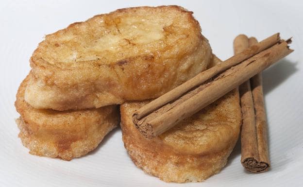 Some French toast served with two cinnamon sticks.
