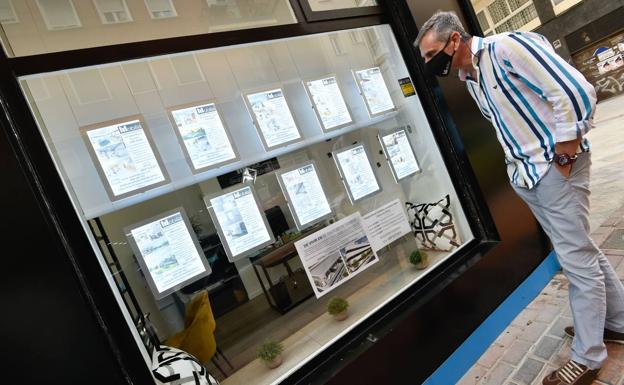 A man looks at the window of a real estate agency in Murcia. 