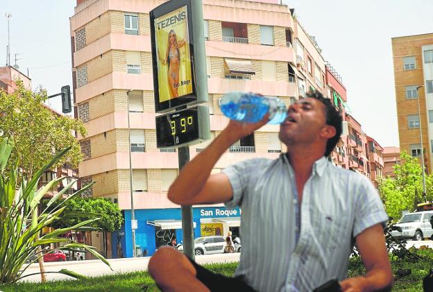 A man drinks water next to a thermometer that shows 39 degrees, in Murcia. 