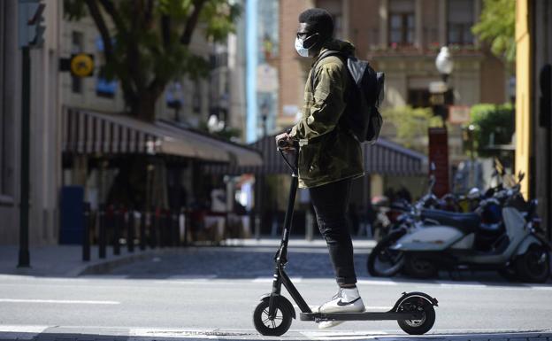 A boy riding around the city with an electric scooter. 