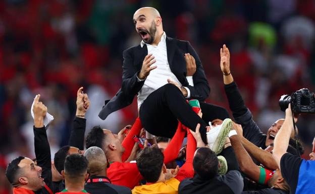 The Moroccan coach, Walid Regragui, blanketed by his players after the victory against Portugal.