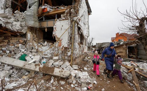 A woman walks with her children through the destruction caused by a Russian airstrike in Hlevakha, outside kyiv. 